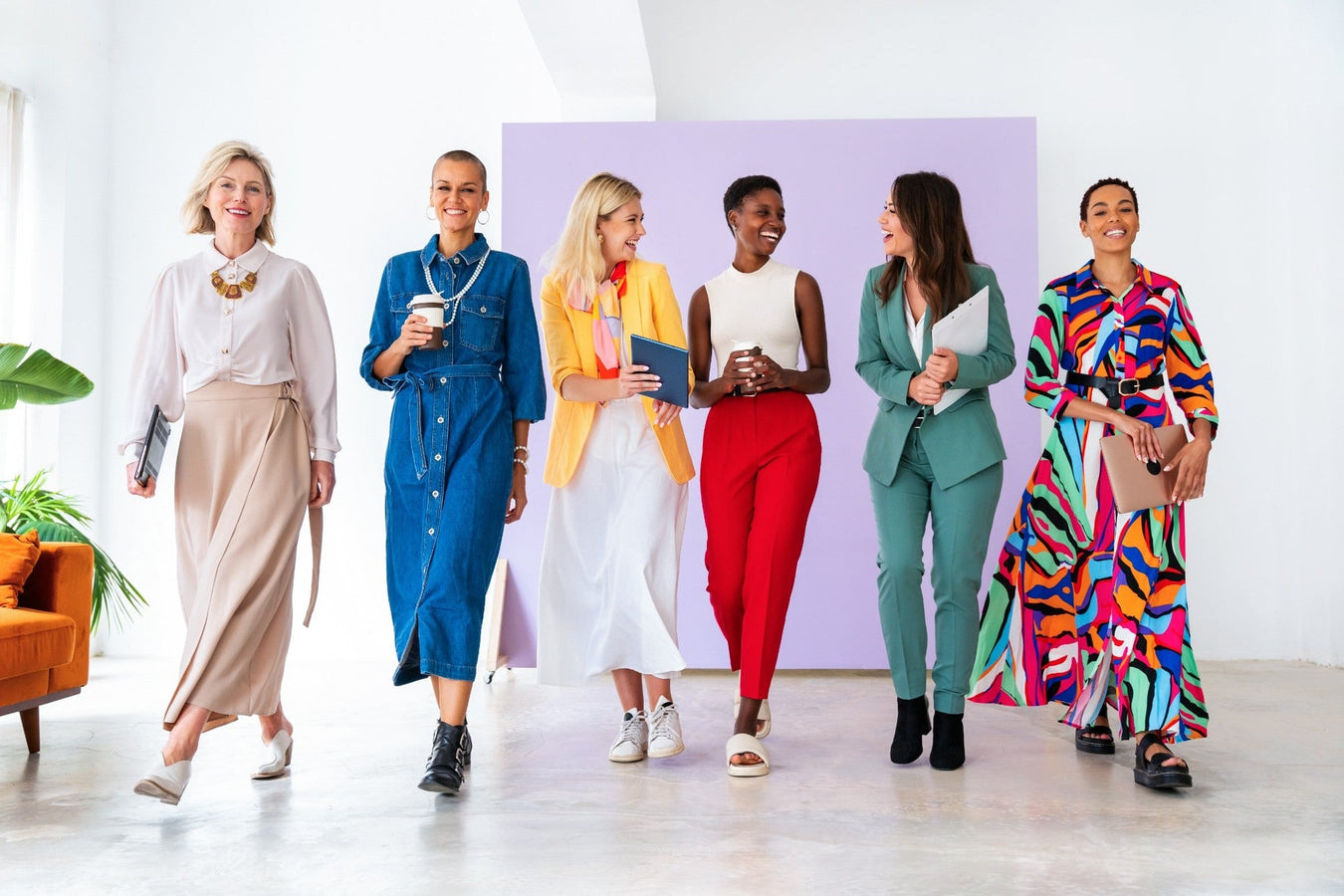 Sechs stilvoll gekleidete Frauen in Business- und Casual-Outfits laufen gemeinsam durch ein modernes Büro – Mode & Accessoires für Damen