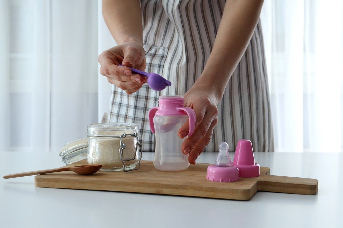 Frau bereitet Babymilch mit Pulver und Babyflasche vor – Ernährung & Stillen bei TECHTRAL