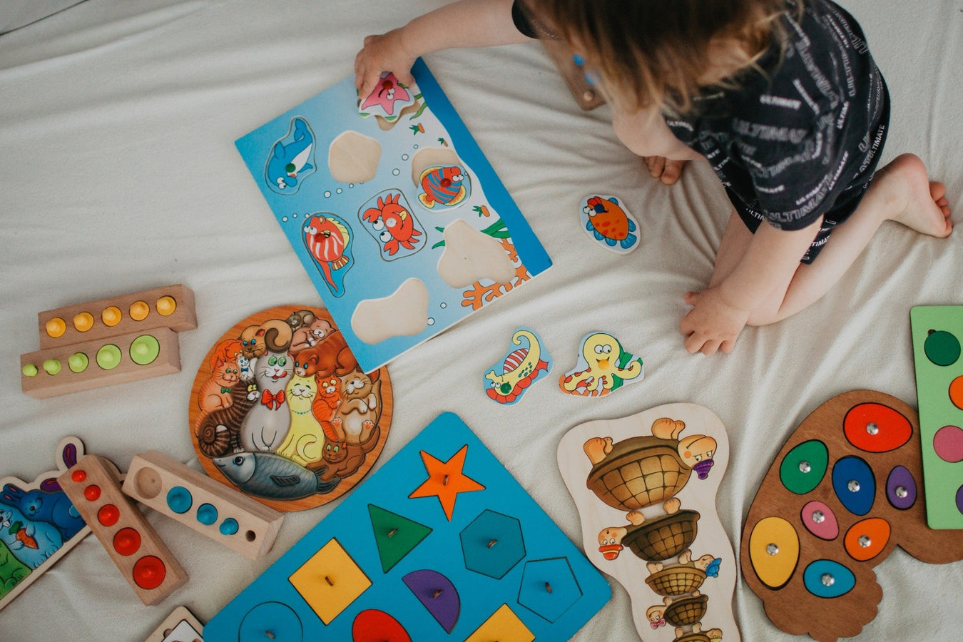 Kleinkind spielt mit bunten Lernspielen und Holzpuzzles zur Förderung der Entwicklung – TECHTRAL Kollektion Lernen & Entwicklung