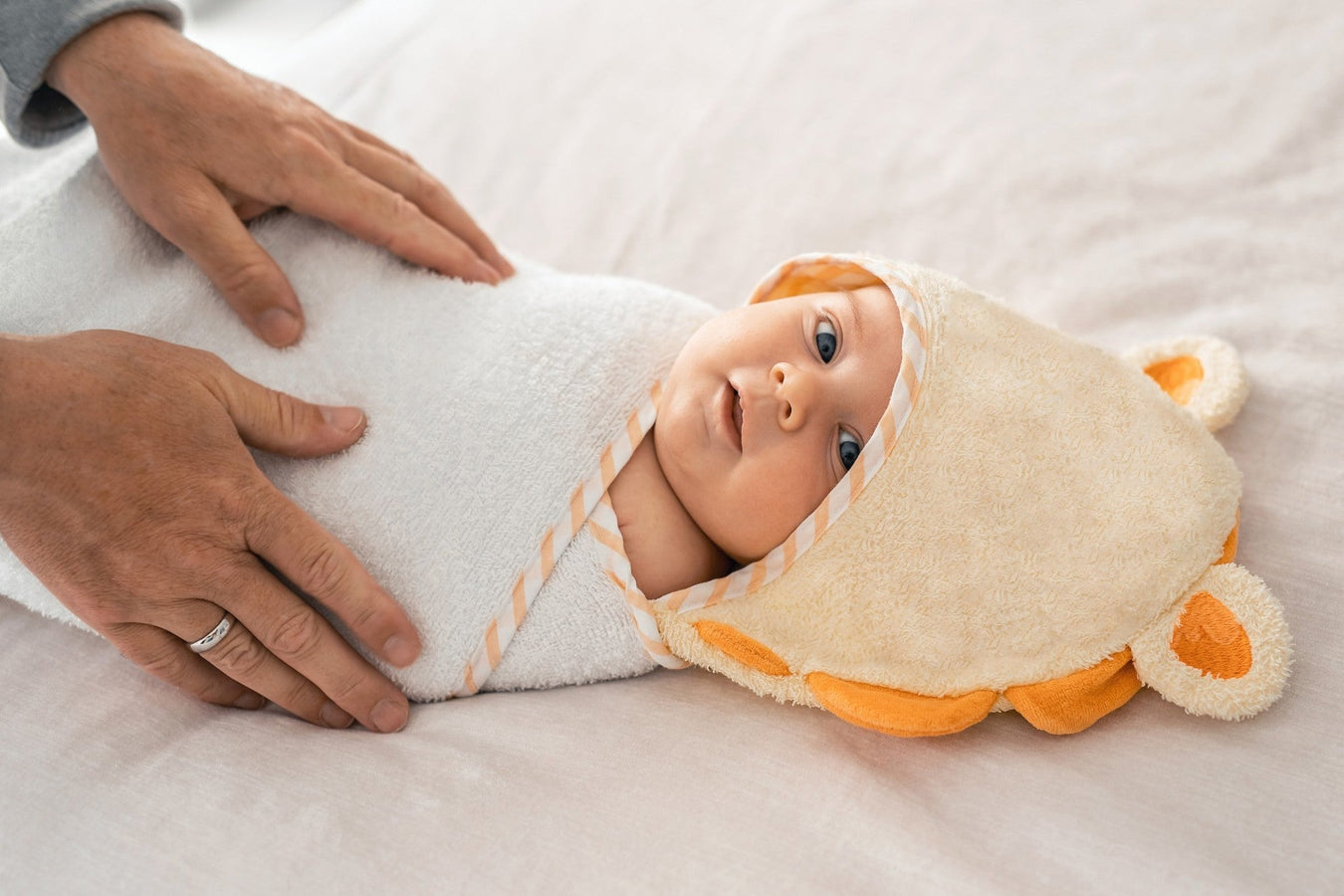 Baby sicher eingewickelt in Kapuzenhandtuch, gehalten von schützenden Elternhänden – TECHTRAL Sicherheit & Zubehör für Kinder